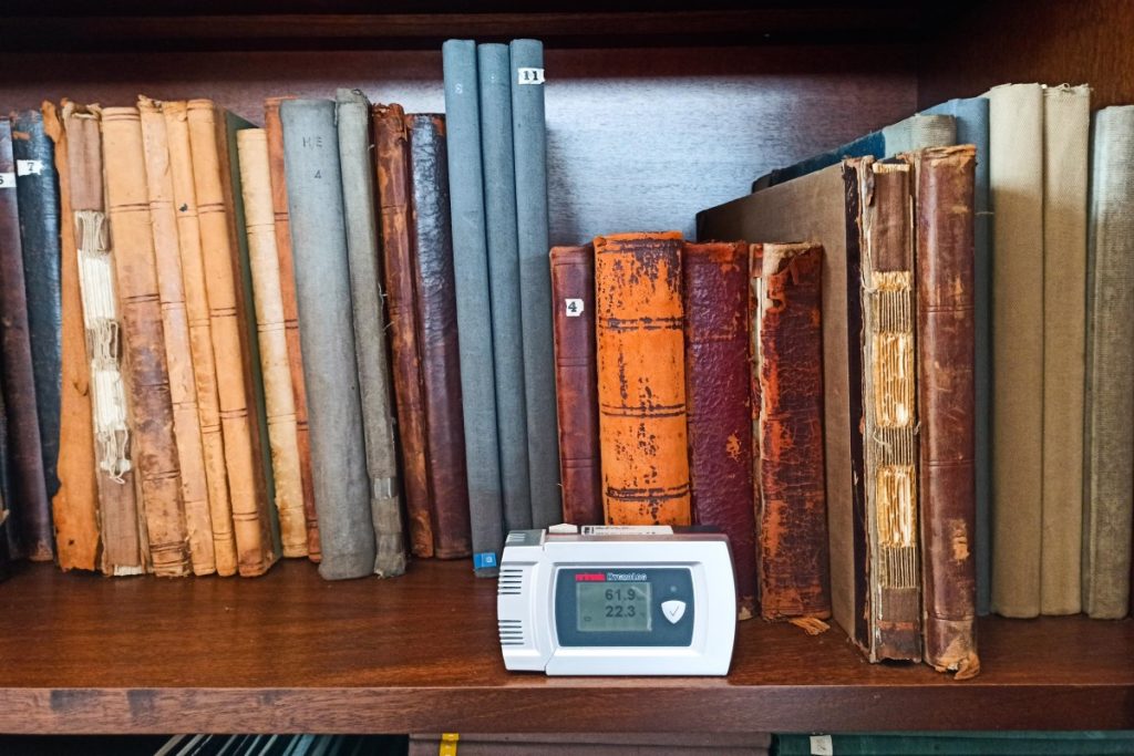 Termohigrógrafo junto de livros antigos numa prateleira