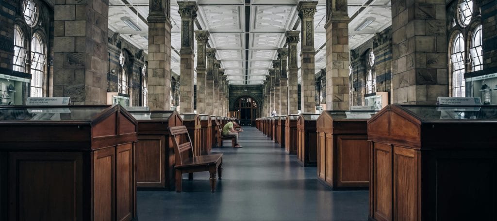 Corredor de um museu com várias vitrines de exposição de objetos museulógicos