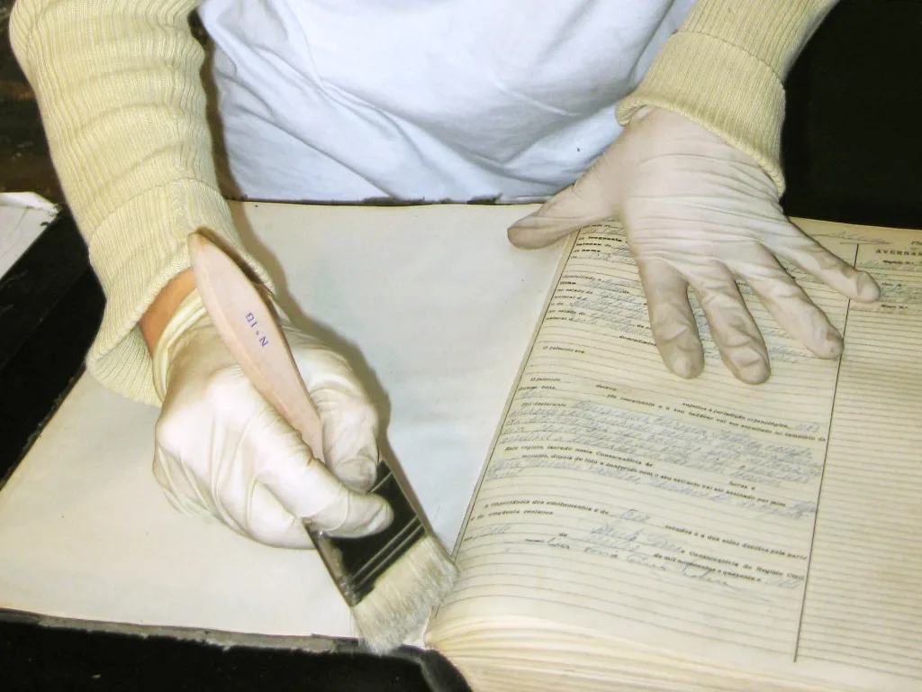 Person using a cleaning brush to clean a paper document